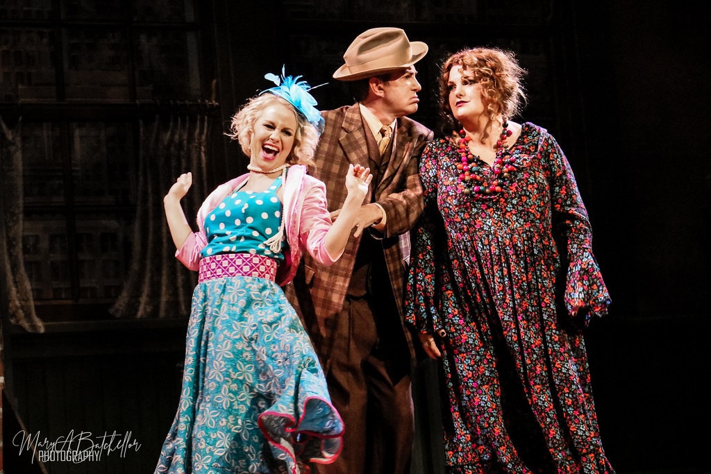 Annie — Lily St. Regis laughs with arms raised as Rooster and Miss Hannigan celebrate