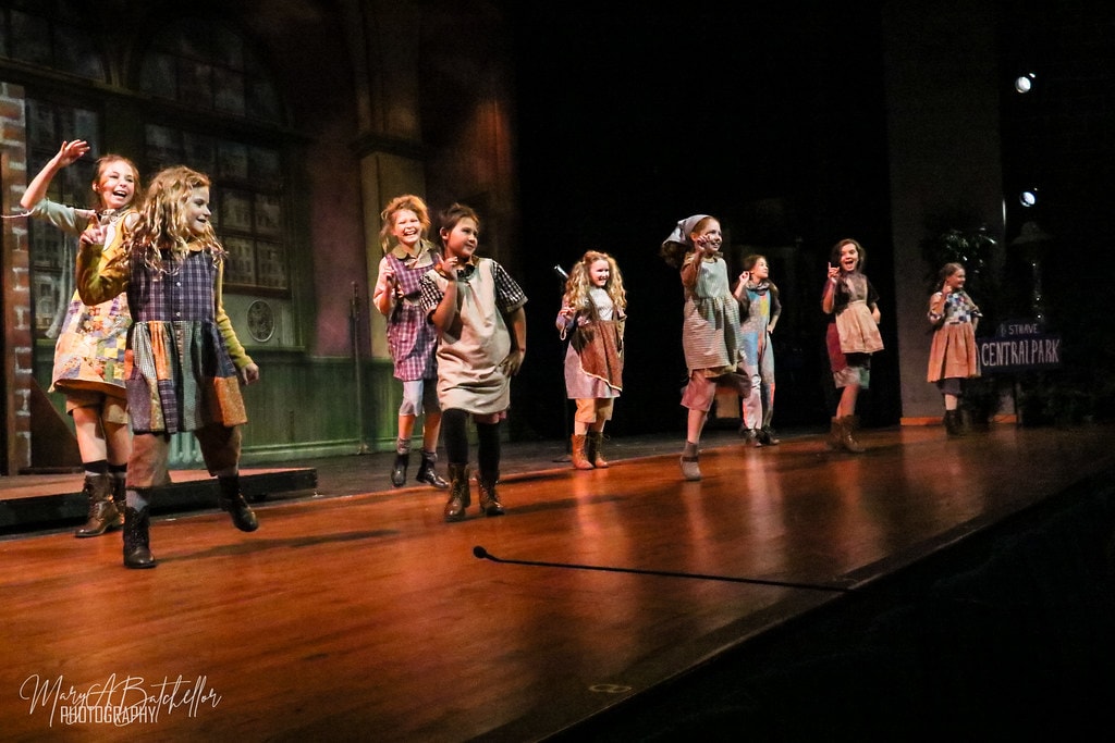 Annie — nine orphan girls skip and dance in a wide line across the full stage