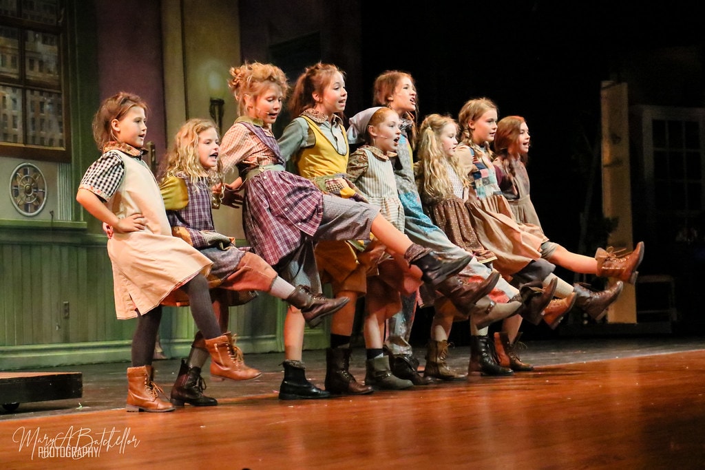 Annie — nine orphan girls kick their legs in a synchronized chorus line