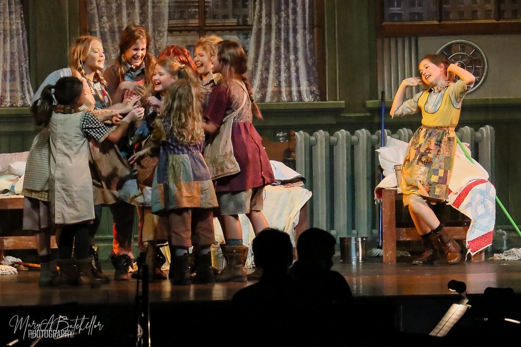 Annie — six orphan girls cluster joyfully around Annie as she dances away laughing