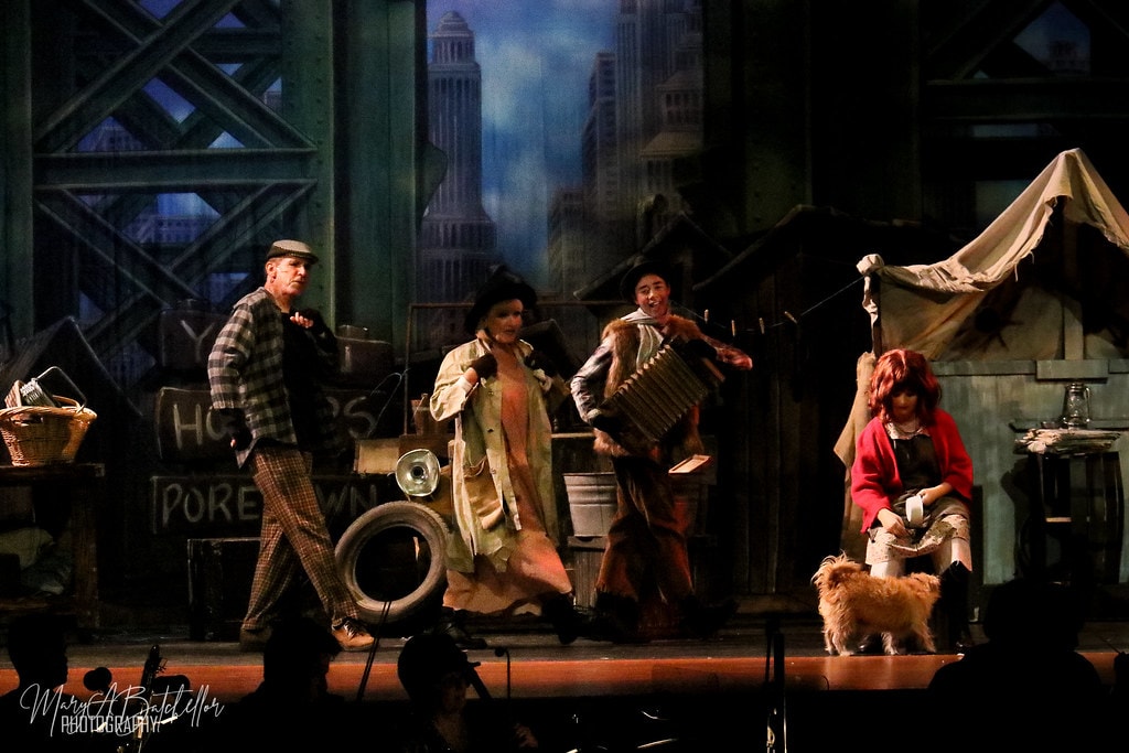 Annie — three adults perform the Hooverville number with an accordion player as Annie sits with Sandy