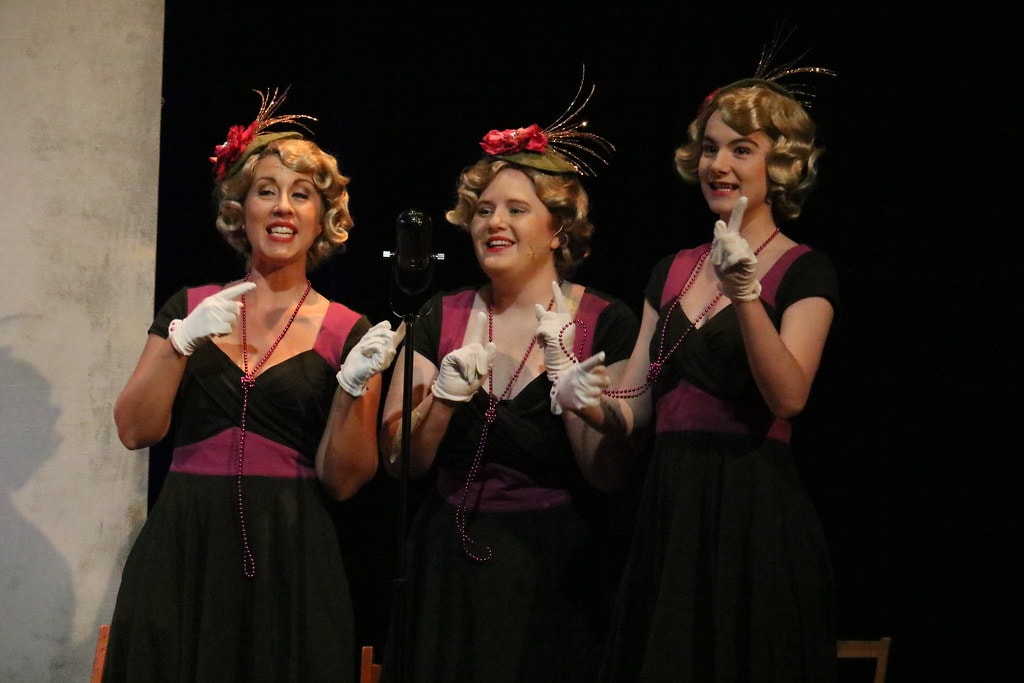 Annie — three women in matching black and magenta 1930s dresses sing a trio — second angle