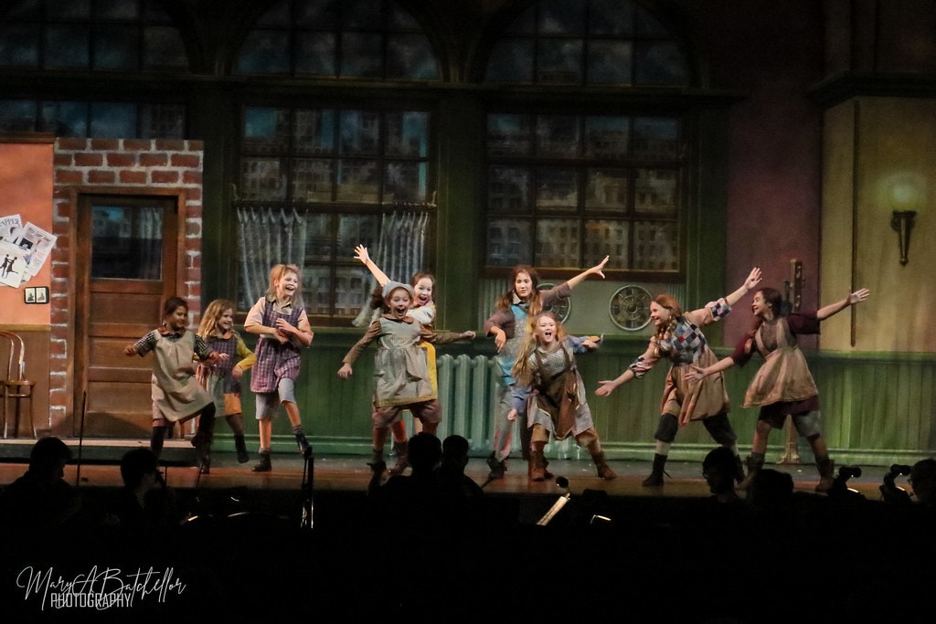 Annie — nine orphan girls dance joyfully with arms raised before the Warbucks apartment set — second angle