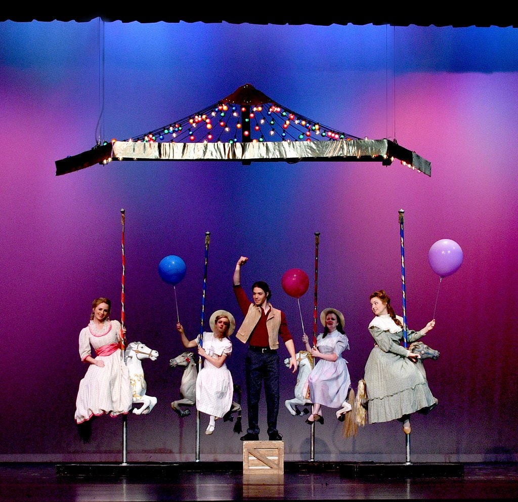 Lit carousel with horses and Billy standing on crate — Carousel