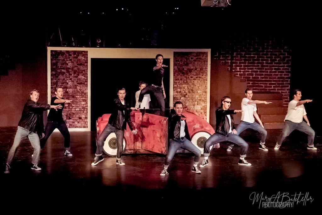 Grease — full T-Birds ensemble in wide formation around red car