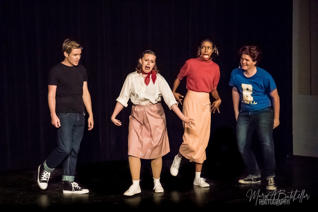 Grease — four performers in comedic number on dark stage second angle