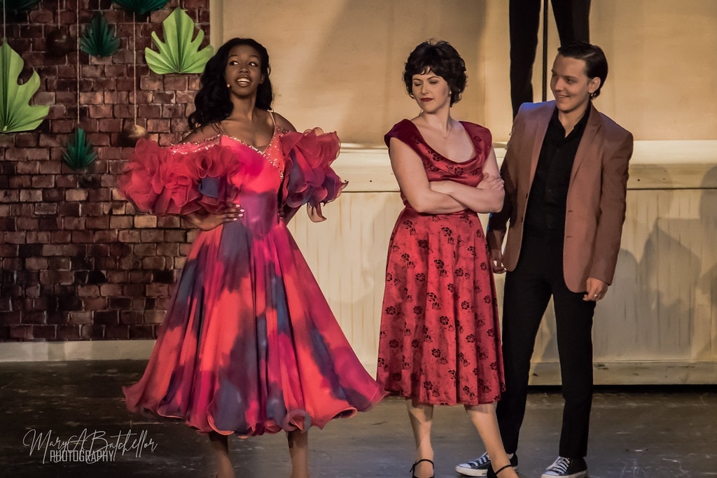 Grease — three performers at beach party set with tropical backdrop