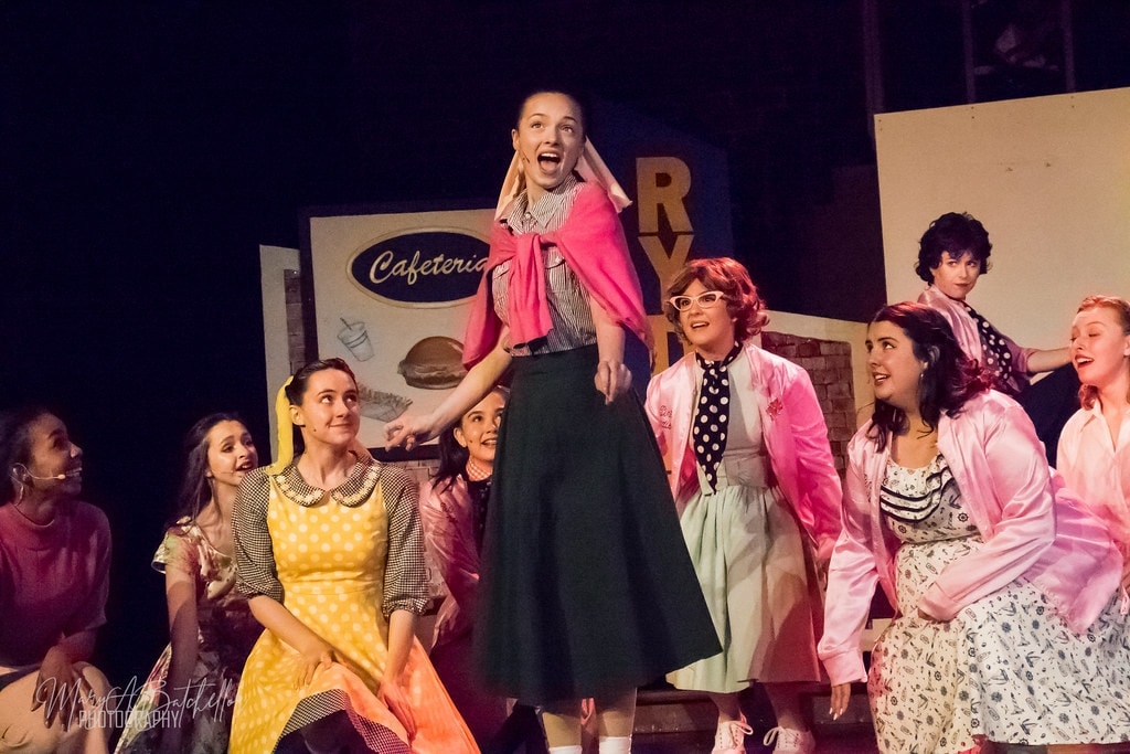 Grease — Sandy elevated center stage in pink cardigan