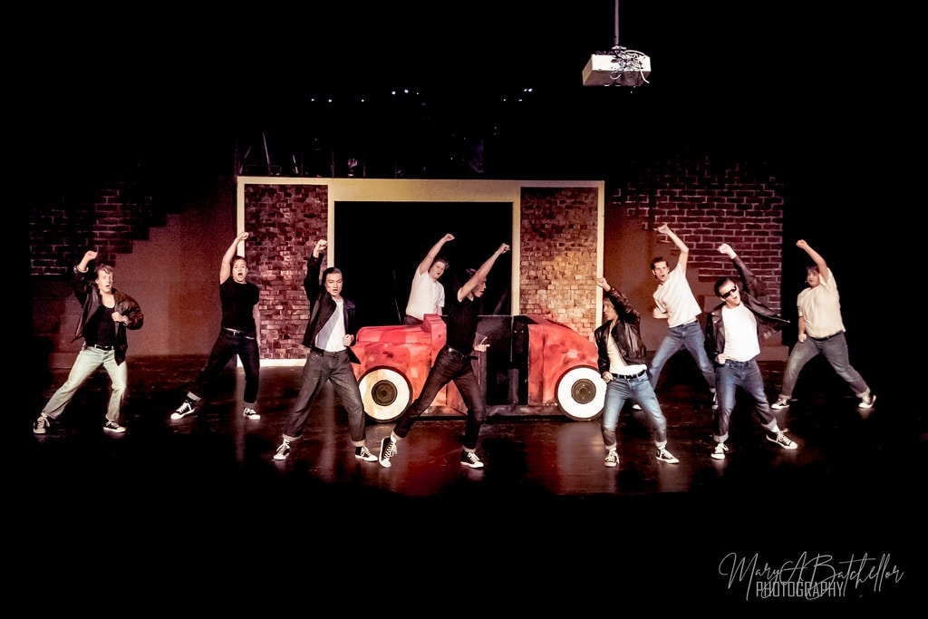 Grease — full T-Birds ensemble with fists raised around the red car