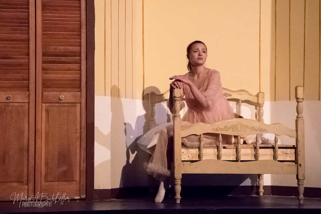 Grease — Sandy in pink nightgown sitting pensively at the foot of her bed