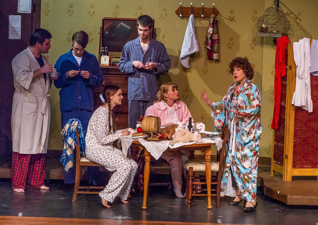 Gypsy — six performers in the boarding house set: three men in pajamas and robes stand at left as a young woman in a floral nightgown sits at the table with a white rabbit, a woman in a pink robe, and Rose in her floral kimono gesturing dramatically at right
