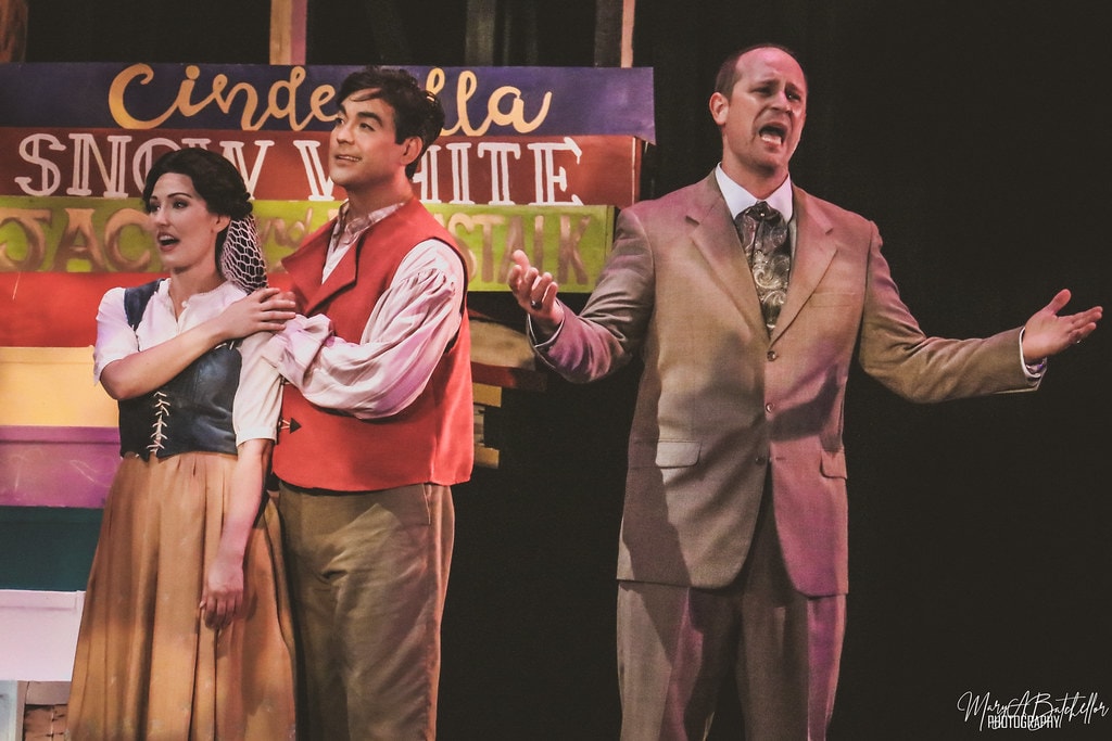Into the Woods — the Baker's Wife, the Baker, and the Mysterious Man sing together before the Cinderella and Snow White storybook backdrop