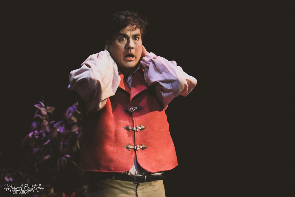 Into the Woods — the Baker in a red vest clutches his head in a dramatic close-up in the dark forest