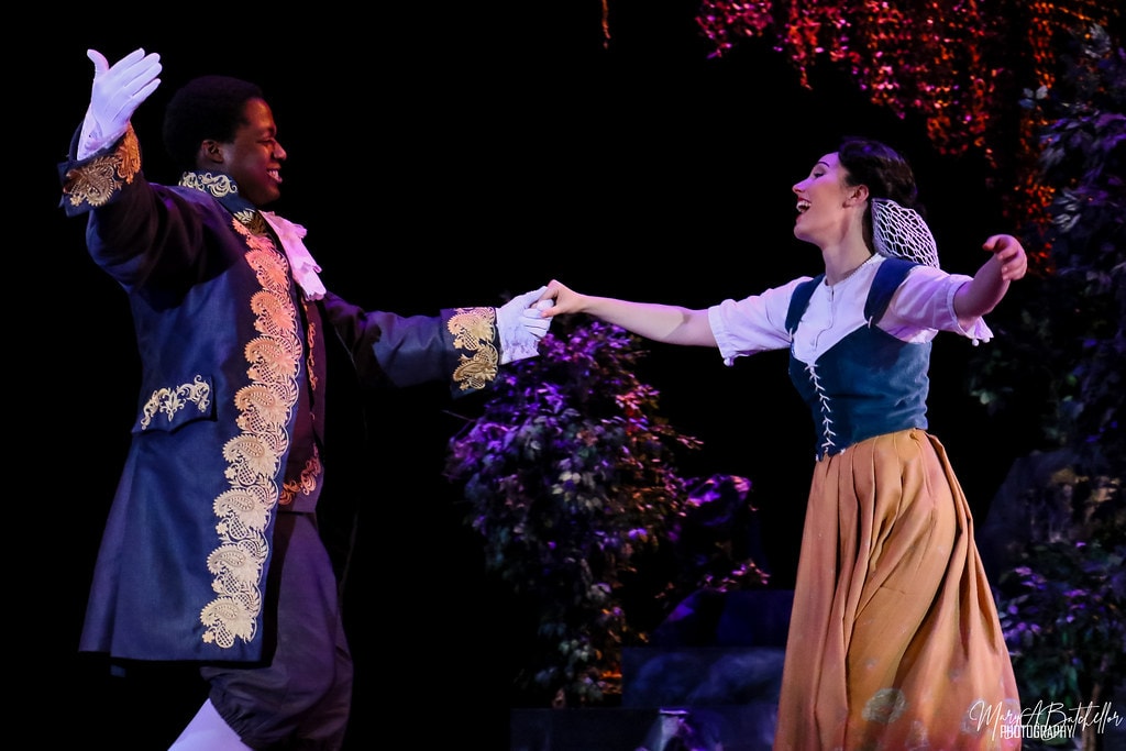 Into the Woods — Rapunzel's Prince and Cinderella hold hands and dance joyfully in the purple-lit forest