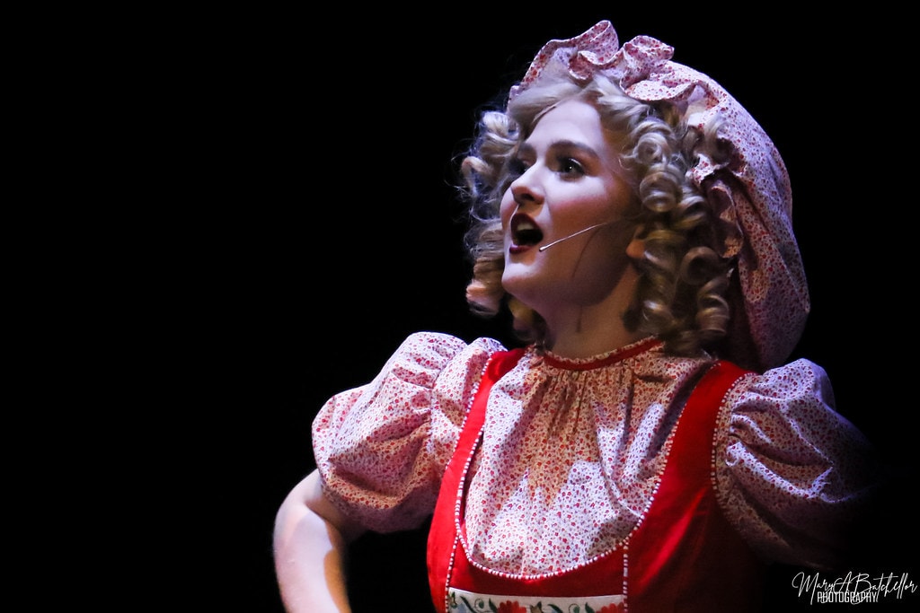 Into the Woods — Little Red Riding Hood in her red cape and floral bonnet belts a dramatic close-up solo