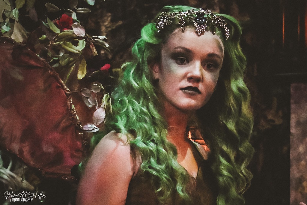 Into the Woods — the Act I Witch in a dramatic close-up portrait with long green hair, jeweled crown, and fairy wings