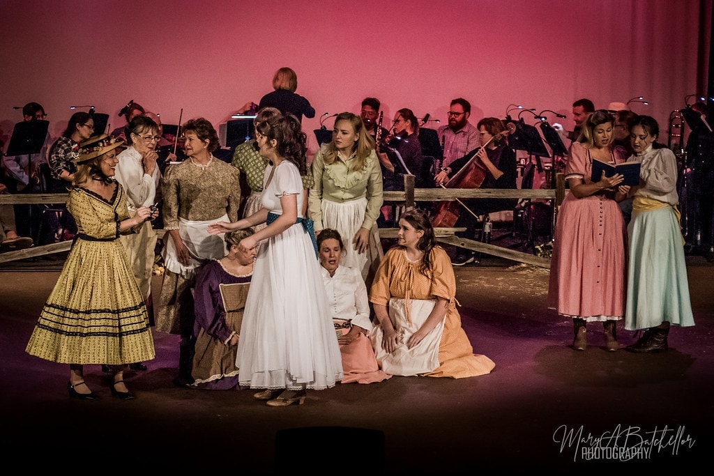 Oklahoma! — ensemble of women in period costumes with orchestra