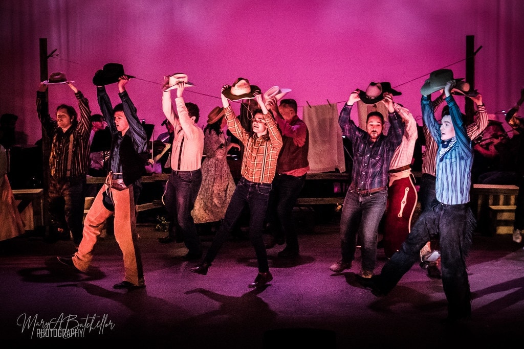 Oklahoma! — male ensemble crowding together in western costumes