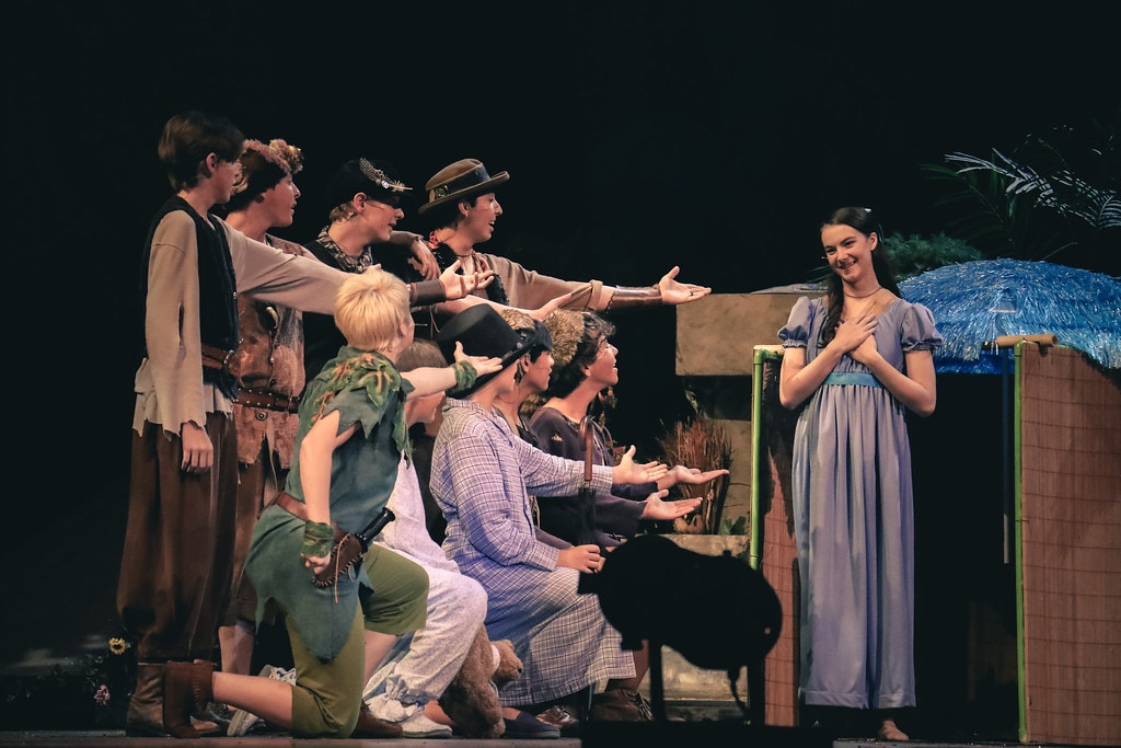 Peter Pan — Peter Pan and the Lost Boys reach out toward Wendy in her blue gown in the Neverland hut scene