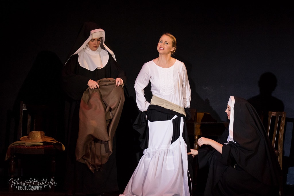 The Sound of Music — Maria standing confidently as two nuns help dress her