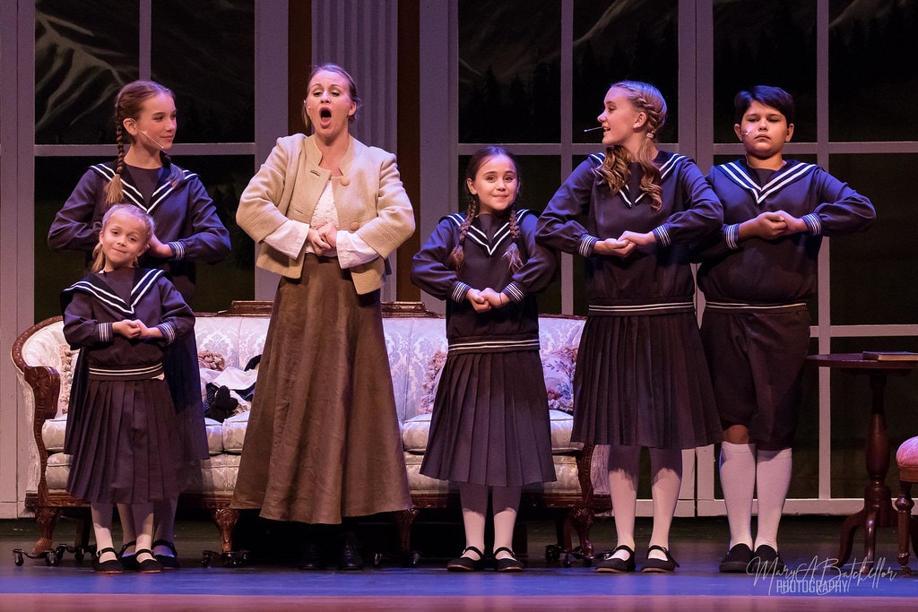 The Sound of Music — Maria center stage belting with von Trapp children