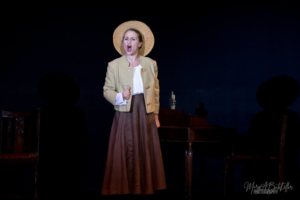 The Sound of Music — Maria in straw hat and tan jacket belting a solo