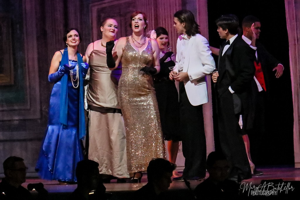 Thoroughly Modern Millie — the full cast in 1920s evening wear performs a grand ensemble number before the ornate ballroom backdrop