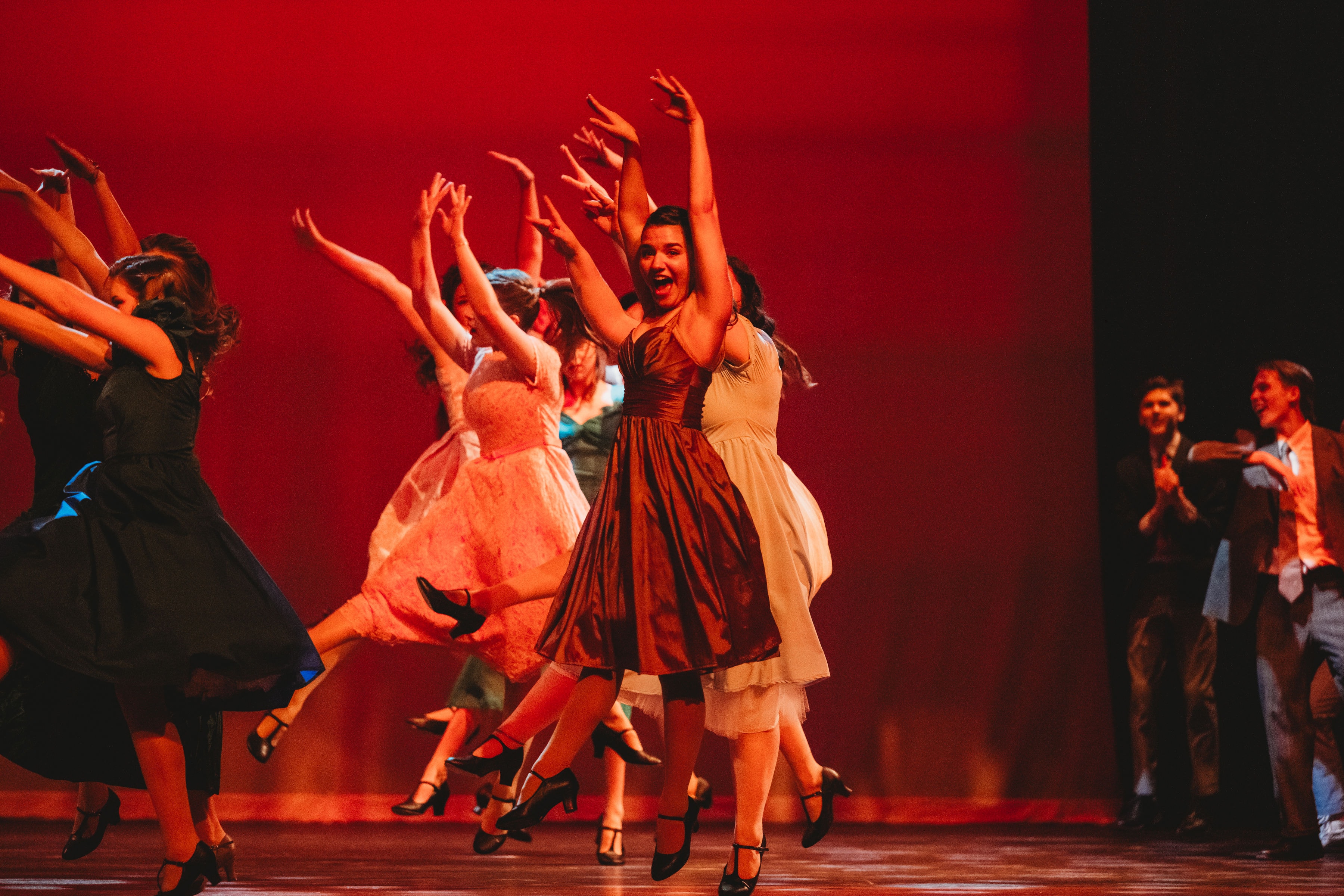 West Side Story 2026 - female ensemble dancing with arms raised in red lighting